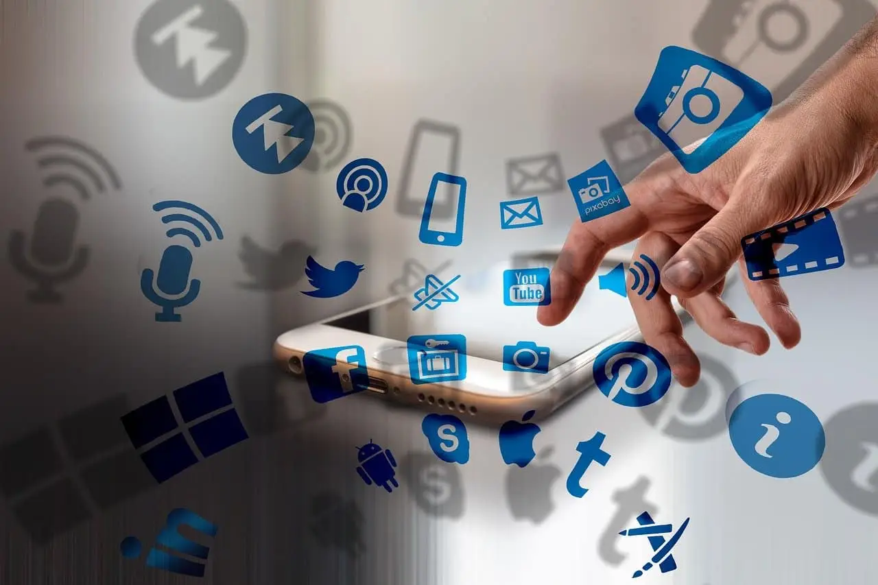 Mano tocando iconos de aplicaciones digitales que flotan sobre un smartphone, representando la digitalización de empresas mediante aplicaciones personalizadas.